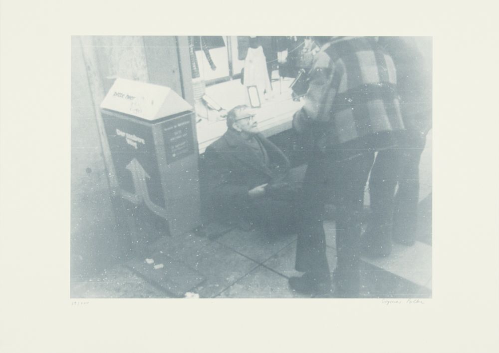 A picture that looks like a faded photograph. The photo shows a man sitting on the floor against the wall.