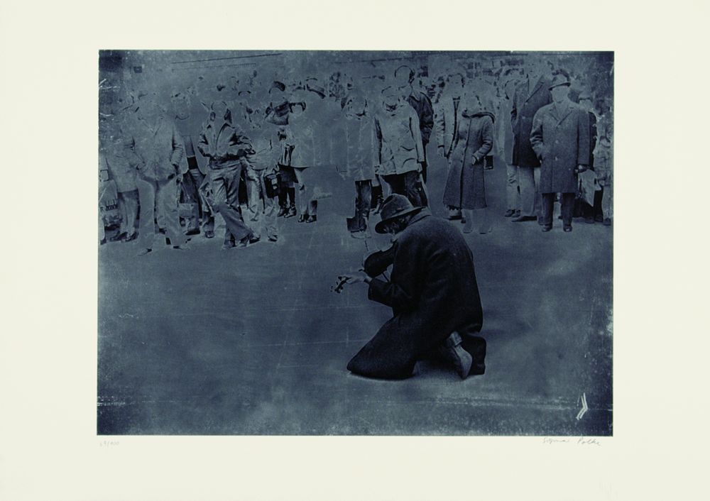 A picture that looks like a faded photograph. In the photo you can see a man kneeling on the floor playing the guitar.