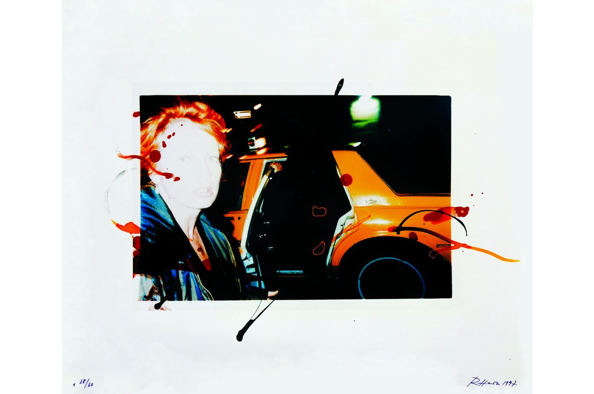 A photo of a red-haired person and a car is positioned in the middle of the picture. There are splashes of different colors of paint scattered across the photo.