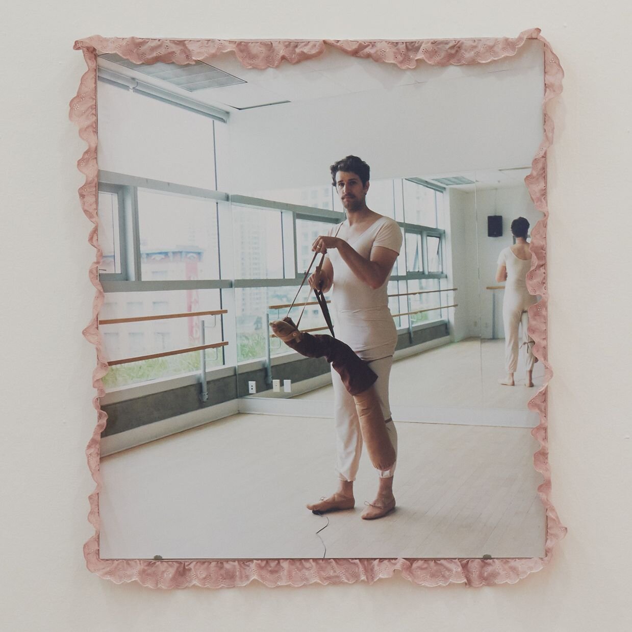Picture of the artist Mike Bourscheid in pink ballet clothes with a sausage made of fabric in a ballet studio