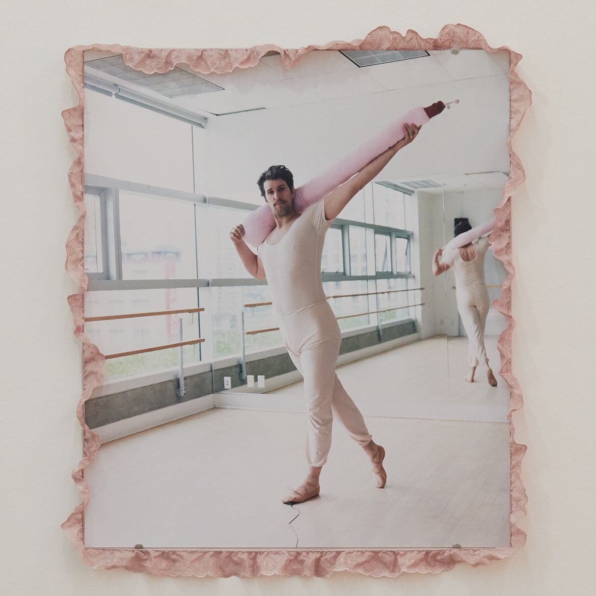 Picture of the artist Mike Bourscheid in pink ballet clothes with a sausage made of fabric in a ballet studio