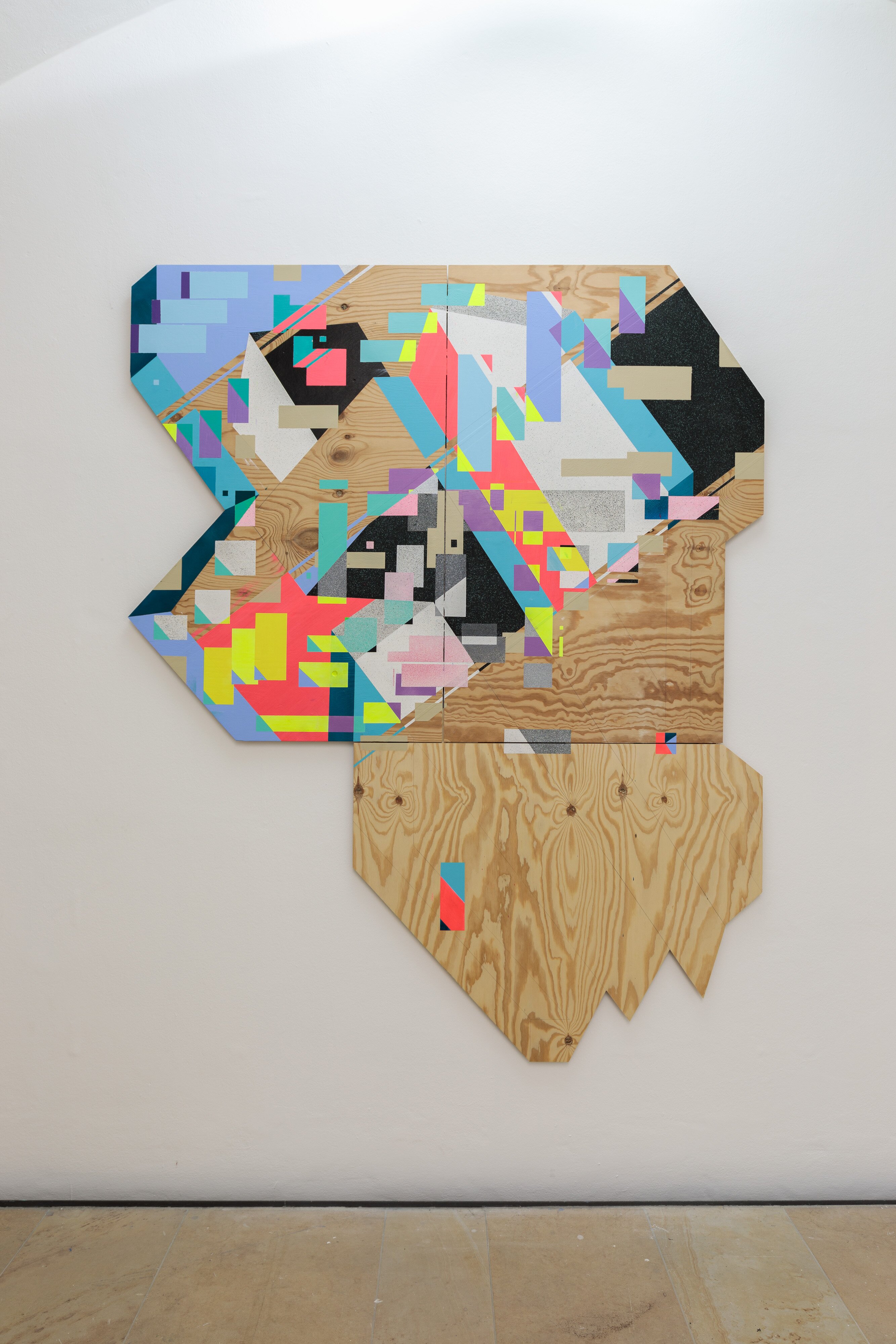Unregelmäßig geschnittene Holzplatte mit vielfarbigen geometrischen Mustern an einer weißen Wand