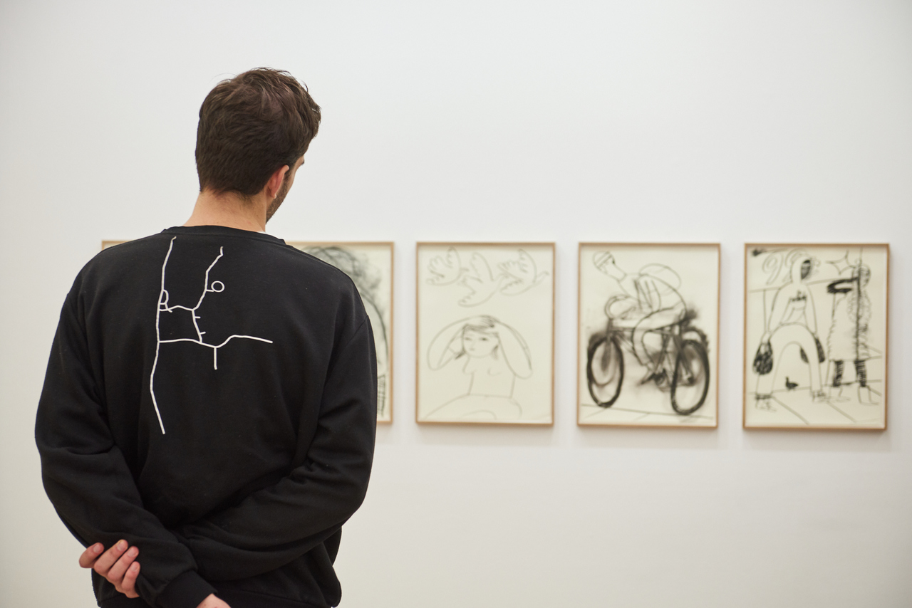 Ein Besucher betrachtet Zeichnungen in der Ausstellung {Grace Weaver. OK}.