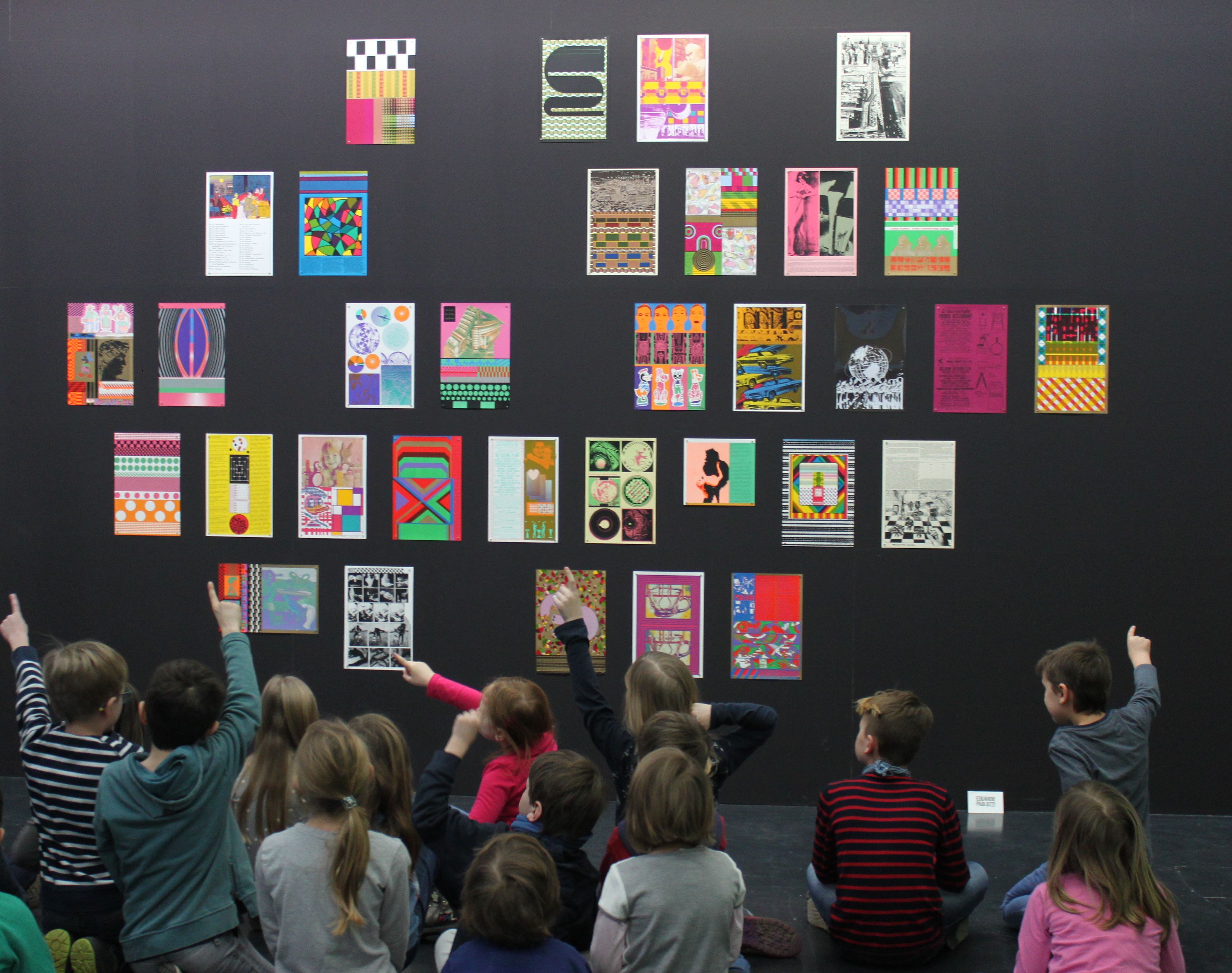 Kinder betrachten gemeinsam mit einer Kunstvermittlerin ein Werk von Eduardo Paolozzi.